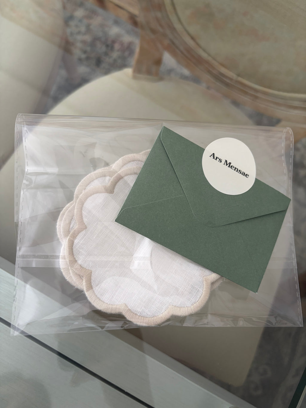 Set of 6 scalloped linen coasters in a clear sleeve with a green envelope and Ars Mensae sticker