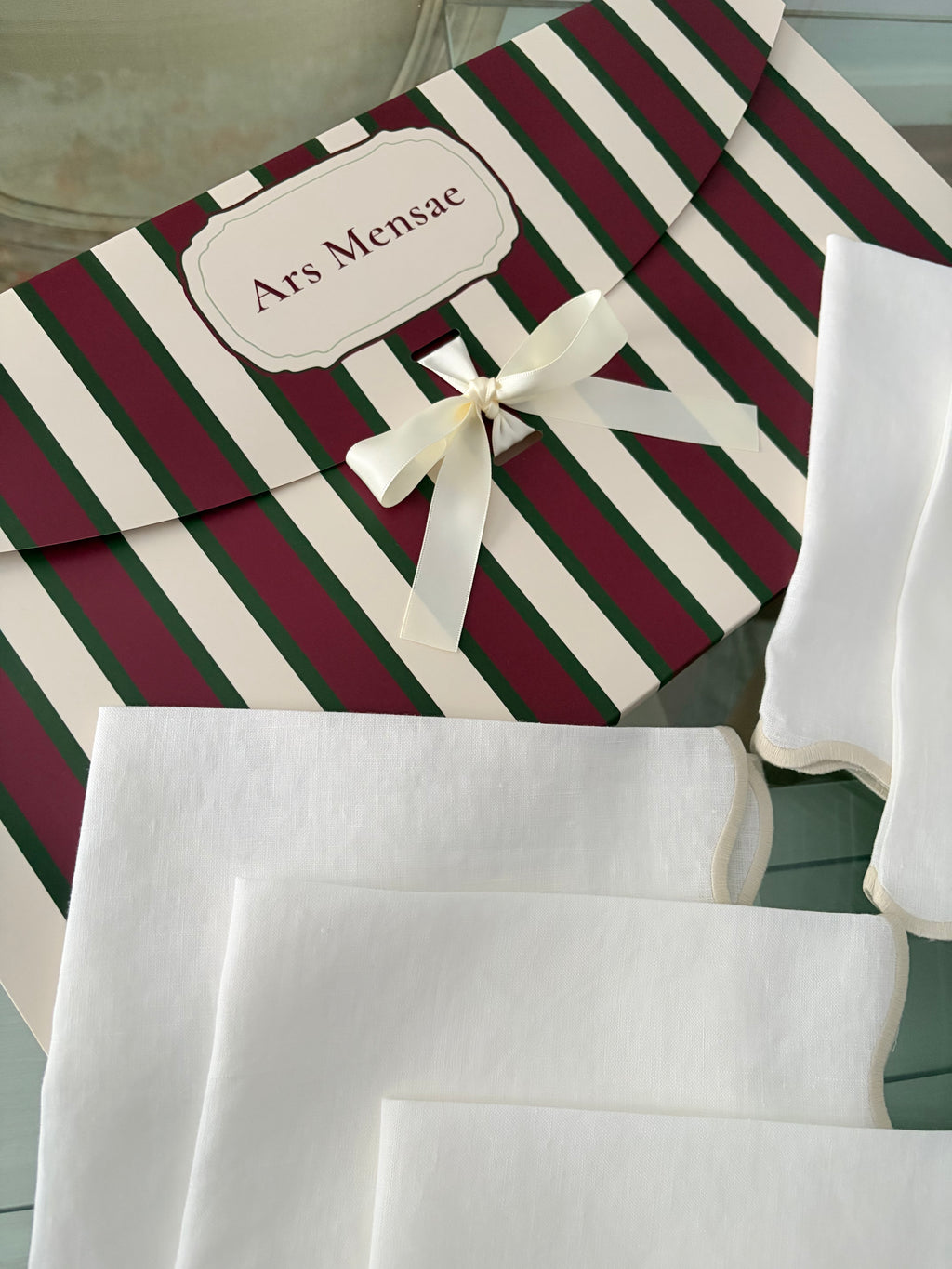 Ars Mensae gift box in burgundy and green stripes with ivory ribbon and scalloped linen napkins